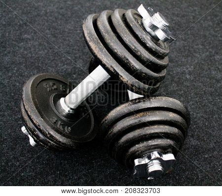 Two black dumbbells on a black carpet