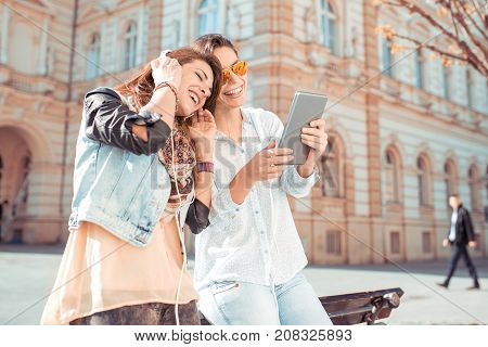 Young woman friends using tablet and listening music from tablet ,technology addicted concept.