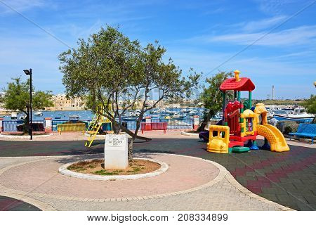BIRZEBBUGA, MALTA - APRIL 1, 2017 - Childrens playground with the harbour to the rear Birzebbuga Malta Europe, April 1, 2017.
