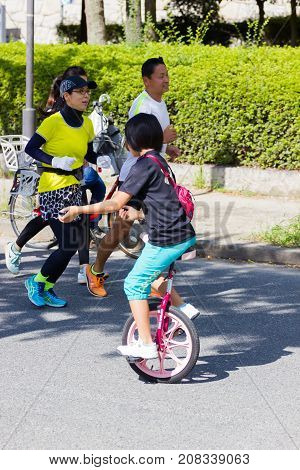 OSAKA JAPAN - SEPTEMBER 18 : unidentified asian little girl riding a unicycle (one wheel bike) in a park on September 18 2017 in Osaka Japan.