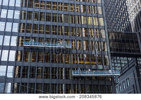 two window cleaning crews working in different heights at office towers in the financial district downtown Toronto