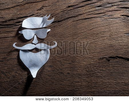 Hipster's definicial facial look cut from paper on the wooden background.