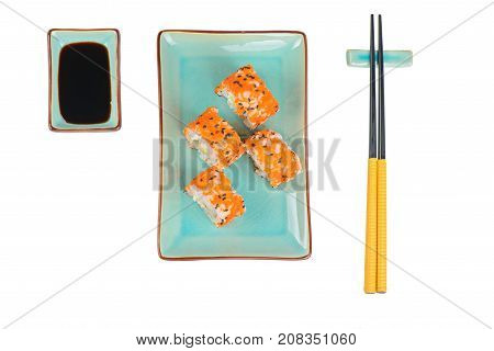 Sushi rolls with masago and soy sauce, served on turquoise plate and chopsticks over isolated white background. Top view.