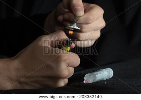 The man prepares drugs with spoon and lighter hepatitis C and AIDS risk