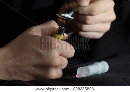 The young man prepares drugs with spoon and lighter