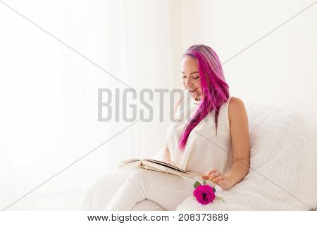 the girl with the pink hair is reading a book in a white room 1