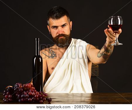 Man With Beard Holds Glass Of Wine On Brown Background.