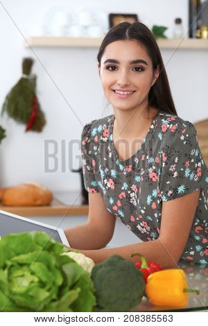 Young hispanic  woman is making online shopping by tablet computer and credit card. Housewife found new recipe for  cooking in a kitchen