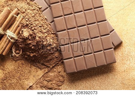 Chocolate bars cocoa and cinnamon sticks on paper