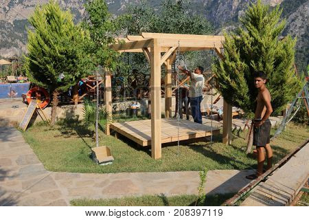 20TH JULY 2017, KABAK,TURKEY: Turkish workmen building a swing seat pergola in an olive garden at kabak, turkey, 20th july 2017