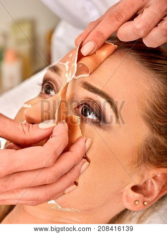 Collagen face mask. Facial skin treatment. Woman receiving cosmetic procedure in beauty salon. Bottle with moisturizing cream on background. Cropped shot of removing wrinkles. Removing black dots.