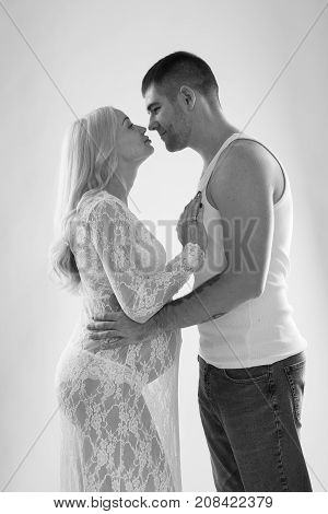 Beautiful pregnant couple in love on the background. Hands of husband on the tummy of his pregnant wife. Young man tenderly stroked pregnant belly of his wife. Husband kissing pregnant belly.
