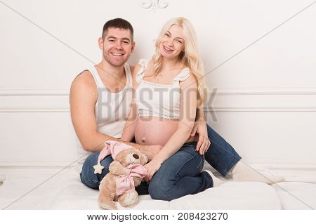 Beautiful pregnant couple in love on the background. Hands of husband on the tummy of his pregnant wife. Young man tenderly stroked pregnant belly of his wife. Husband kissing pregnant belly.