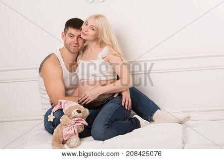 Beautiful pregnant couple in love on the background. Hands of husband on the tummy of his pregnant wife. Young man tenderly stroked pregnant belly of his wife. Husband kissing pregnant belly.