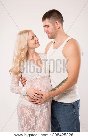 Beautiful pregnant couple in love on the background. Hands of husband on the tummy of his pregnant wife. Young man tenderly stroked pregnant belly of his wife. Husband kissing pregnant belly.