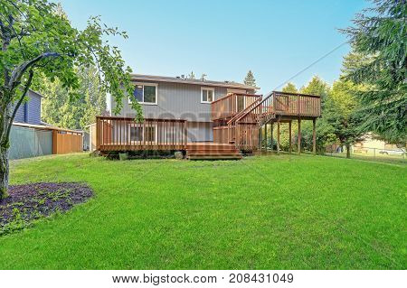 Backyard View Of Grey Rambler House With Upper And Lower Decks