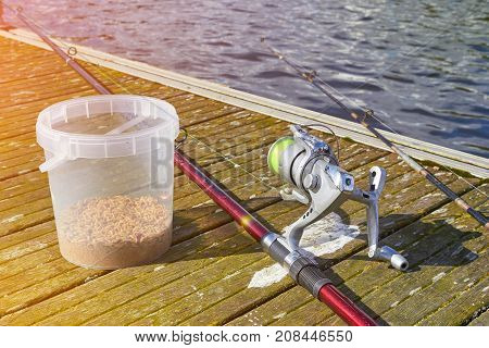 Fshing rod and bucket of bait on the wooden pier