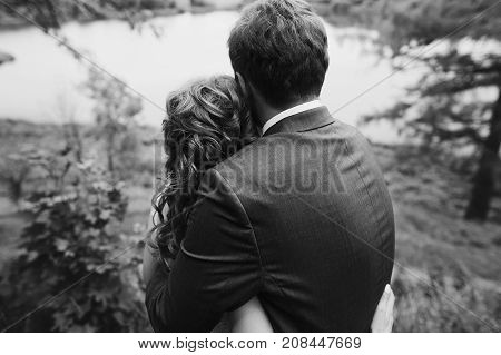 Beautiful Gorgeous Bride And Groom Walking In Sunny Park And Embracing. Happy Wedding Couple Hugging