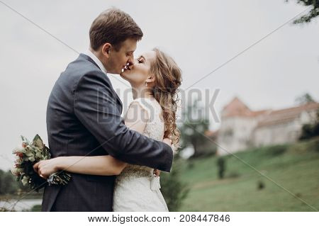 Beautiful Gorgeous Bride And Groom Kissing. Happy Wedding Couple Hugging And Embracing At Old Castle