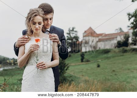 Groom  Hugging Beautiful Gorgeous Bride With Poppy Flower. Happy Sensual Wedding Couple Embracing In