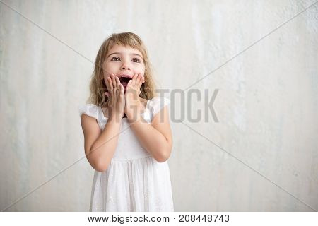 Funny Kid In White Dress Jumping And Laughing On Colored Background. Little Pretty Girl Isolated On