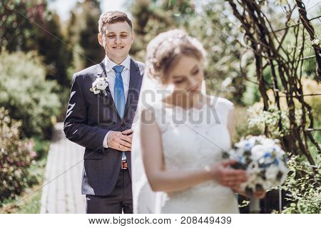 Beautiful Gorgeous Bride And Groom Walking In Sunny Spring Park And Enjoying Day. Happy Wedding Coup
