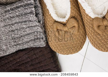 Handmade Warm Knitted Socks From Rough Wool Yarn Fluffy Fir Slippers on White Plank Wood Background. Winter Autumn Eco Fashion Kinfolk Style. Natural Materials.