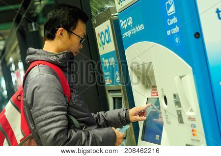 SYDNEY AUSTRALIA -AUGUST 14 2017: Passenger buying train ticket using vending machine at Central railway station Sydney Australia.