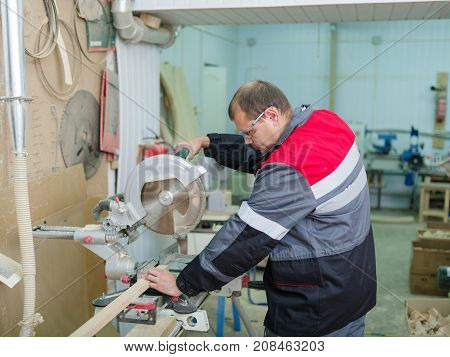 Gray machine circular saw with protection so as not to harm yourself, against the background of the fire extinguisher