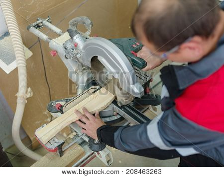 Gray machine circular saw with protection so as not to harm yourself, against the background of the fire extinguisher