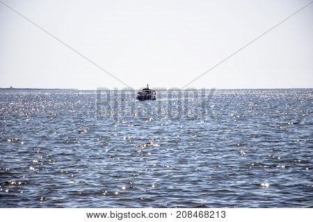 The fishing boat sails to the shore under the rays of the sun