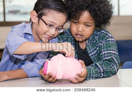 Little Boys Putting Money Into Piggy Bank For Future Savings