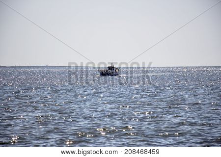 The fishing boat sails to the shore under the rays of the sun