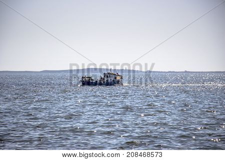 The fishing boat sails to the shore under the rays of the sun