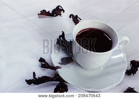 white porcelain mug with tea karkade on white tulle