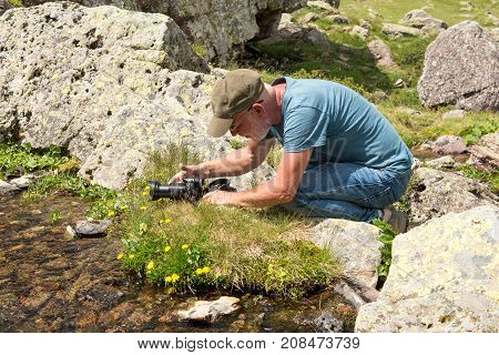 a hiker with camera taking picture of small stream