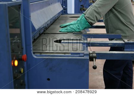 operator bending metal sheet by sheet bending machine, production work process in fabricated factory by worker, manual or semi auto processing.