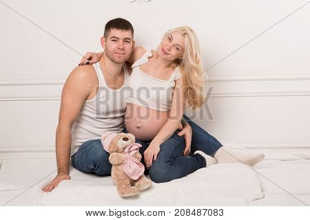 Beautiful pregnant couple in love on the background. Hands of husband on the tummy of his pregnant wife. Young man tenderly stroked pregnant belly of his wife. Husband kissing pregnant belly.
