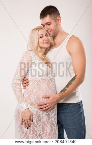Beautiful pregnant couple in love on the background. Hands of husband on the tummy of his pregnant wife. Young man tenderly stroked pregnant belly of his wife. Husband kissing pregnant belly.