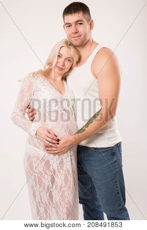 Beautiful pregnant couple in love on the background. Hands of husband on the tummy of his pregnant wife. Young man tenderly stroked pregnant belly of his wife. Husband kissing pregnant belly.