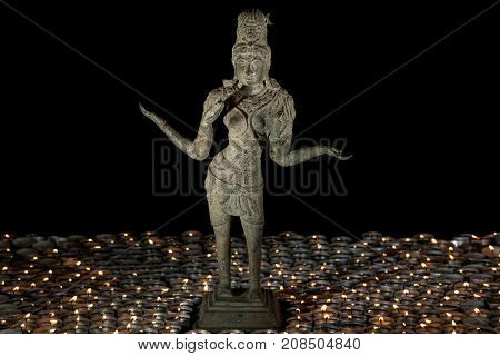 Traditional bronze statue of Lakshmi by candle light. Hindu Goddess of wealth prosperity and fortune. Diwali celebration of the festival of lights.