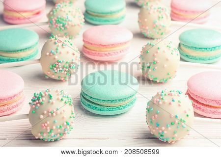 Sweet background of mint and strawberry flavor macaroons and cake pops on sticks
