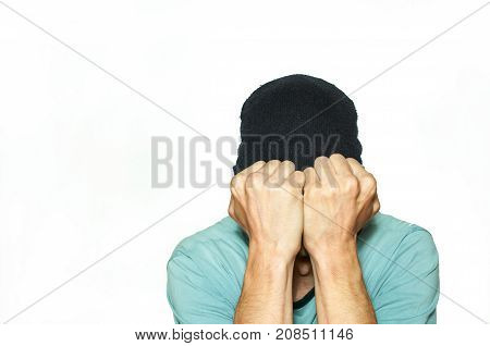 Young man trying to cover his eyes with hat while he suffering from strong migraine headache pain attack isolated on white background