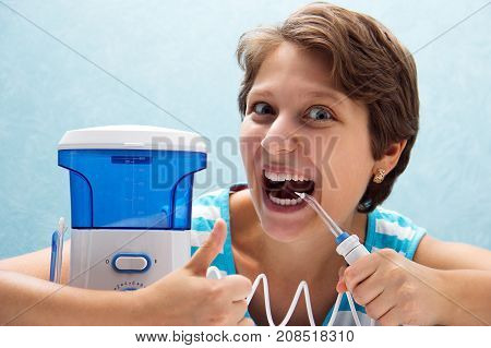 Beautiful And Crazy Girl Opened Her Mouth Wide And Brushed Her Teeth With An Irrigator With A Nozzle
