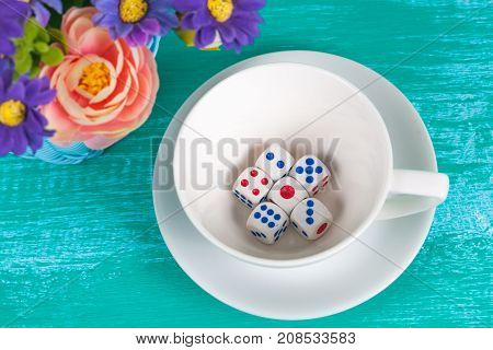 dice in white  cup on color wood