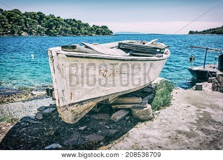 Old fishing boat with cracked white paint Solta island Croatia. Travel destination. Mediterranean scene. Old photo filter.