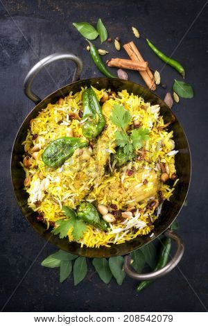 Indian chicken biryani with nuts and raisins as close-up in a korai 