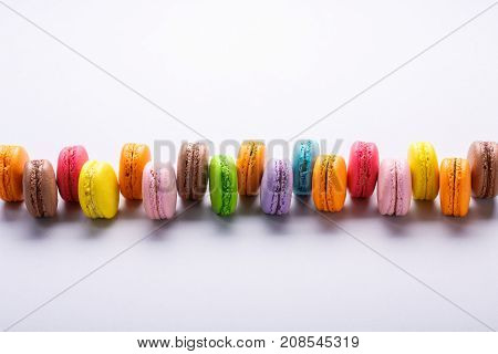 Colorful macarons in a raw on gray background. Macaron or Macaroon is sweet meringue-based confection. Place for text