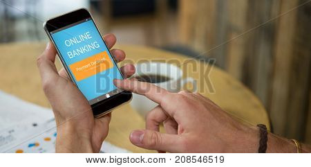 Online banking text on green mobile display against man using mobile phone at table in cafe