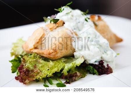 Traditional russian pie - coulibiac. Baked puff pastry filled with smoked salmon, served with sour cream sauce